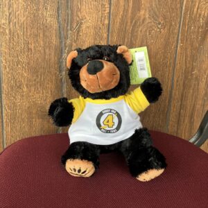 stuffed black bear wearing a white tshirt with yellow trim and the bobby orr hall of fame logo in the centre.