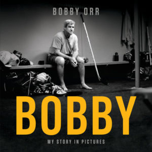 Front cover of the book Bobby: My Story in Pictures featuring Bobby Orr sitting in a hockey dressing room.