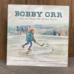 Front cover of Bobby Orr and the Hand-me-down skates book featuring an illustration of a boy skating on a frozen pond with a hockey stick and puck.